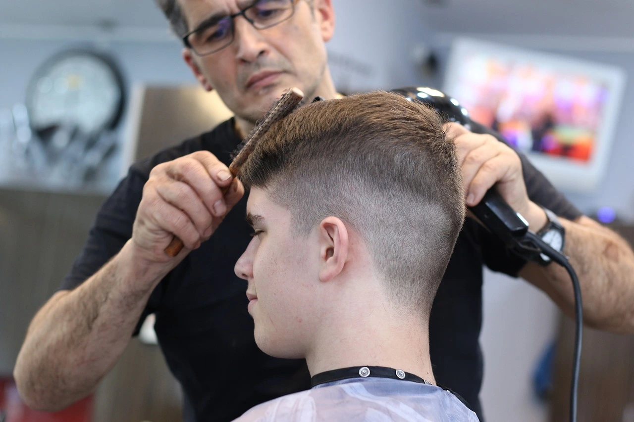 A barber is cutting a boy's hair