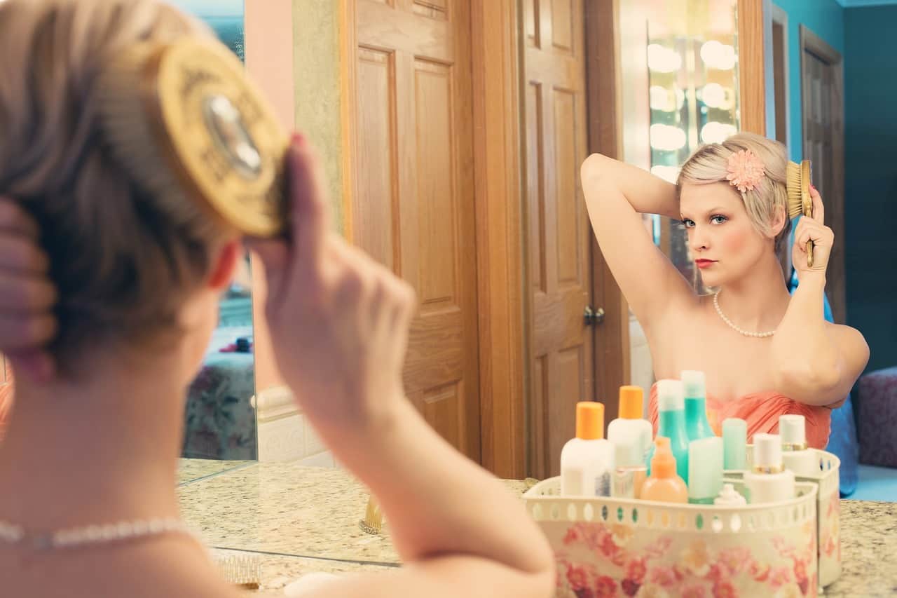 A beautiful woman sitting in front of a mirror combing her hair