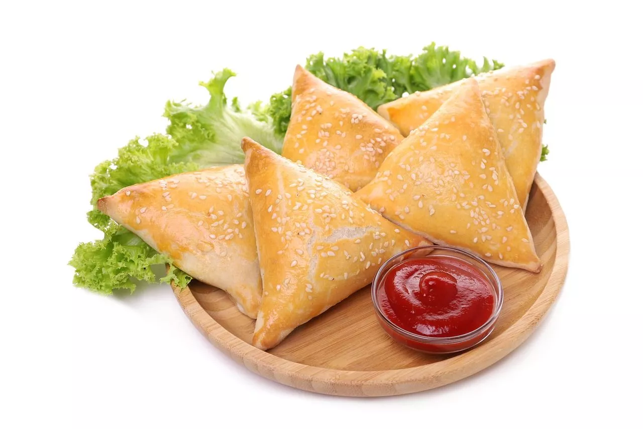 Four samosas topped with red chutney