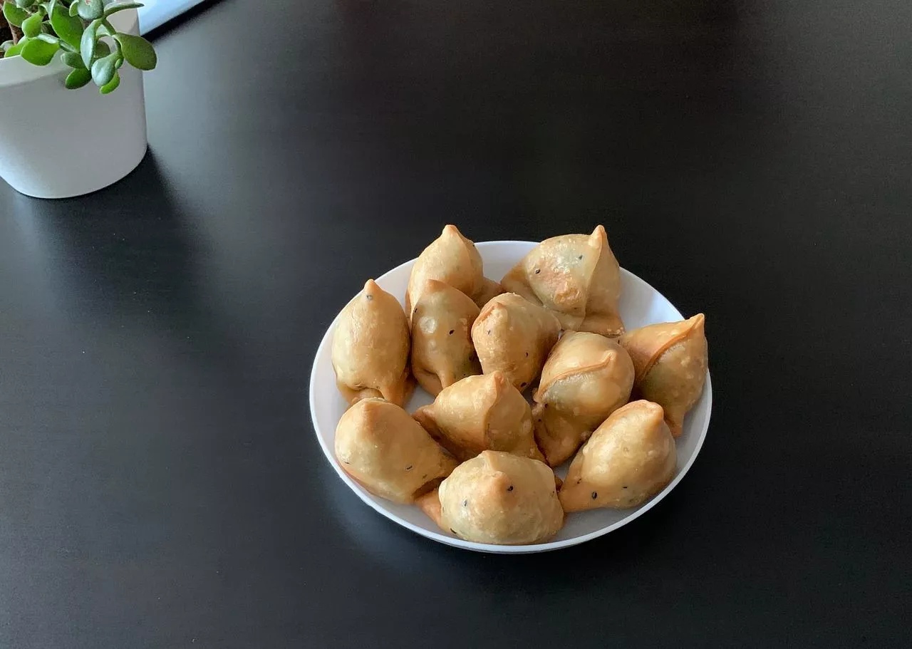 Many samosas are placed on a plate