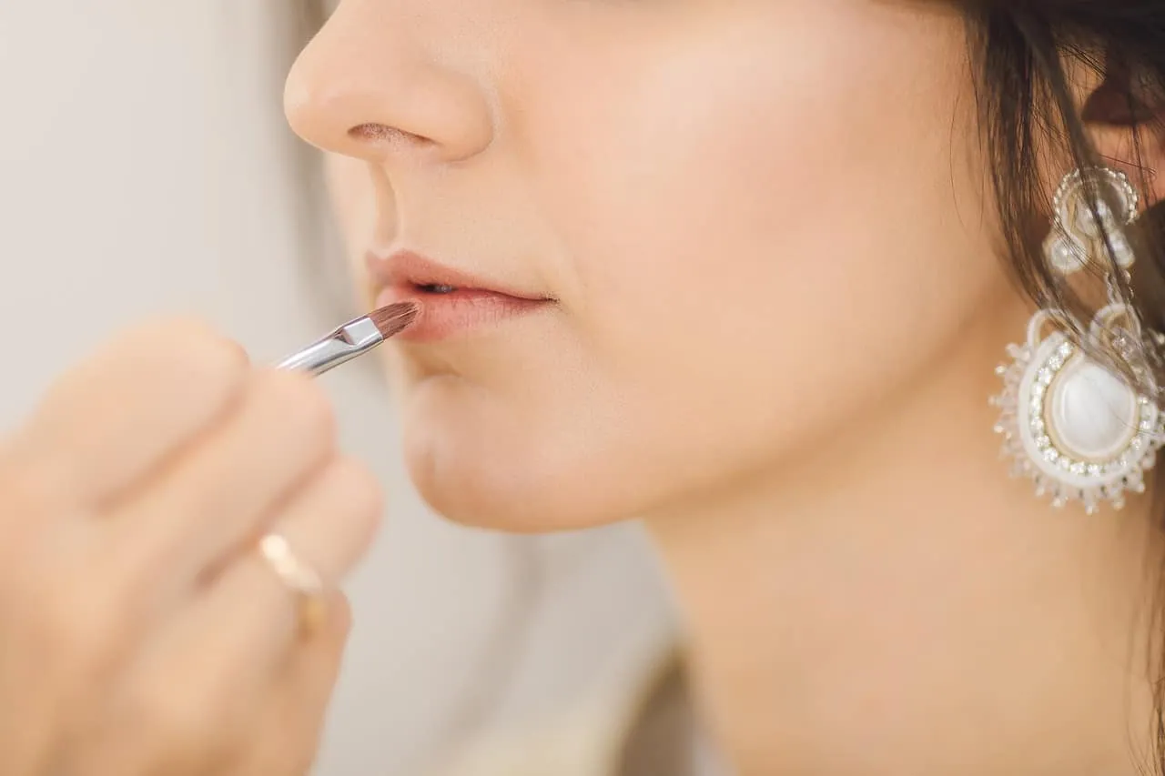 a beautiful woman applying lipstick on her lips
