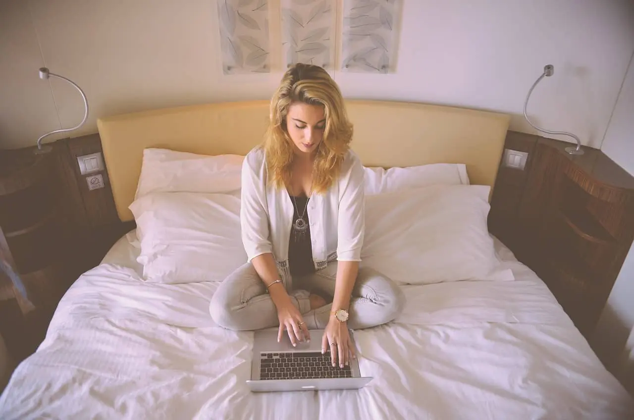 a woman sitting on the bed using a laptop